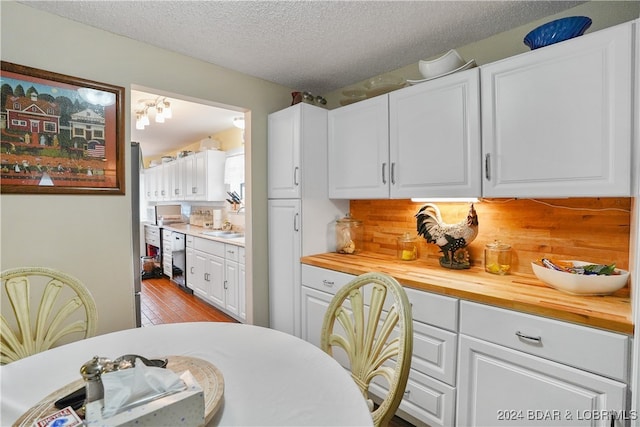 kitchen featuring butcher block counters, sink, light wood-type flooring, a textured ceiling, and white cabinets