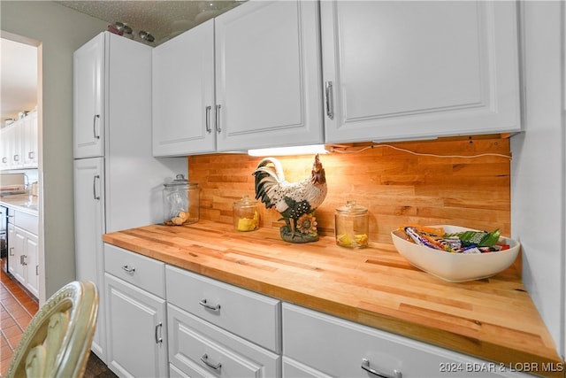 interior space with backsplash, white cabinetry, a textured ceiling, and wooden counters