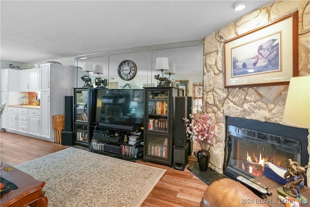 living room with a fireplace, a textured ceiling, and light hardwood / wood-style flooring