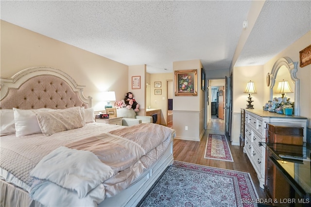 bedroom with a textured ceiling and dark wood-type flooring