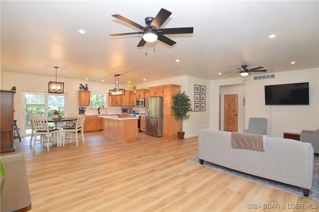 living room featuring ceiling fan with notable chandelier and light hardwood / wood-style floors