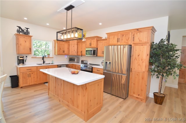 kitchen featuring stainless steel appliances, sink, pendant lighting, light hardwood / wood-style flooring, and a center island