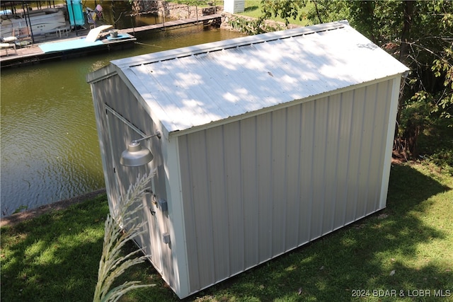 view of outdoor structure with a water view and a lawn