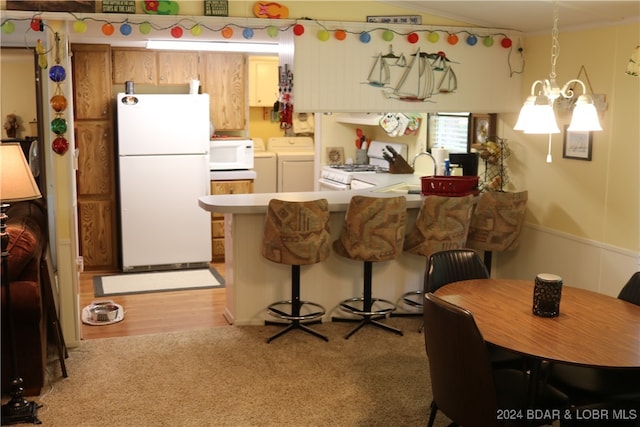 kitchen featuring washing machine and dryer, light wood-type flooring, kitchen peninsula, white appliances, and a notable chandelier