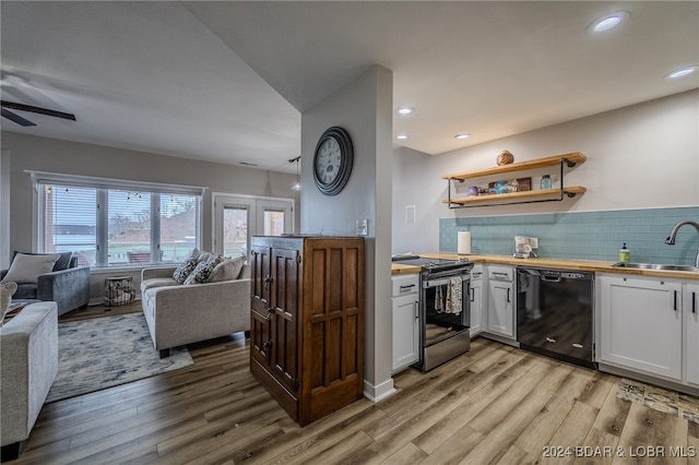 kitchen with butcher block counters, white cabinets, black appliances, sink, and light wood-type flooring