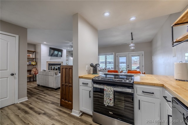 kitchen with a fireplace, butcher block counters, white cabinetry, appliances with stainless steel finishes, and light wood-type flooring