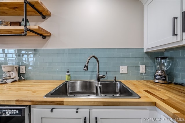 kitchen with white cabinets, wood counters, sink, and backsplash