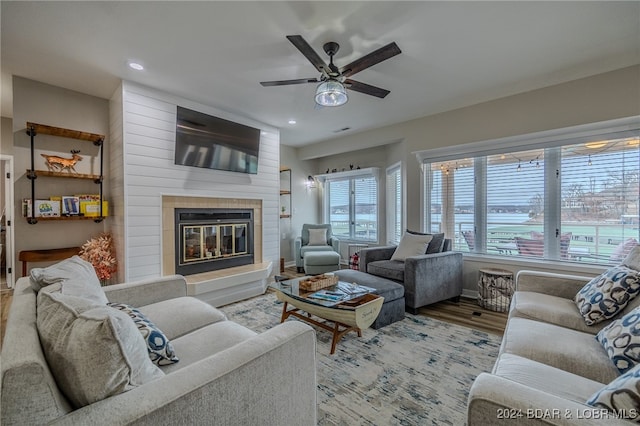 living room featuring ceiling fan, light hardwood / wood-style floors, and a fireplace