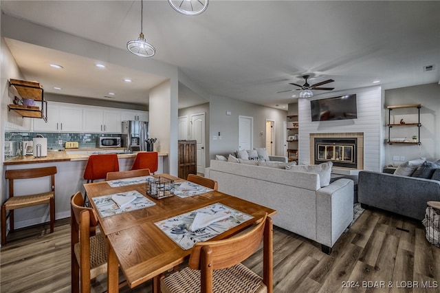 dining space featuring ceiling fan, dark hardwood / wood-style floors, and a fireplace