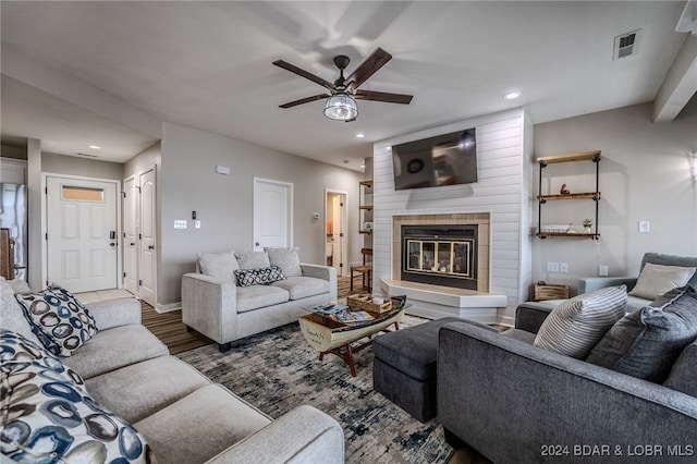 living room featuring wood-type flooring, ceiling fan, and a fireplace