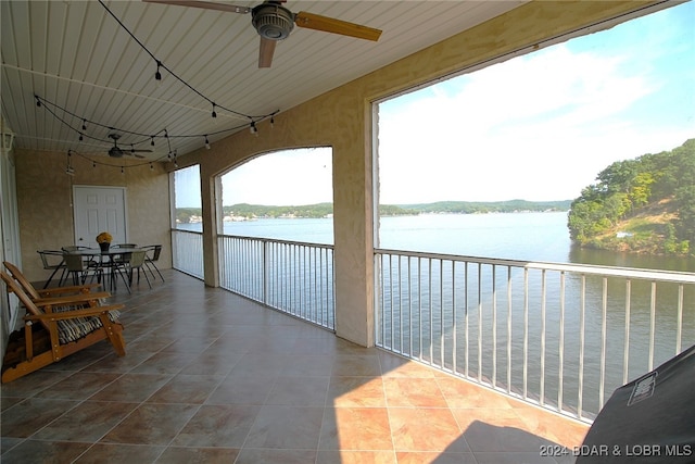 sunroom / solarium featuring ceiling fan, a water view, and track lighting