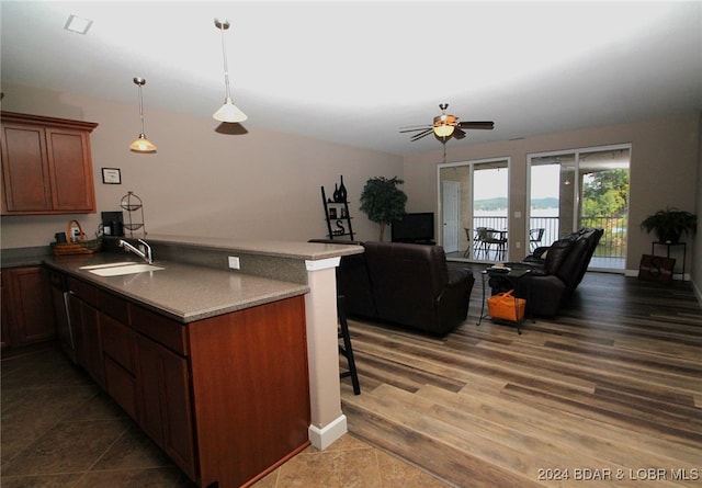 kitchen with dark hardwood / wood-style flooring, a breakfast bar, kitchen peninsula, sink, and ceiling fan