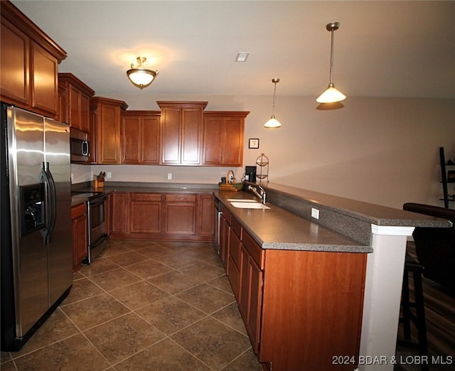 kitchen featuring a kitchen bar, kitchen peninsula, appliances with stainless steel finishes, and dark tile patterned flooring