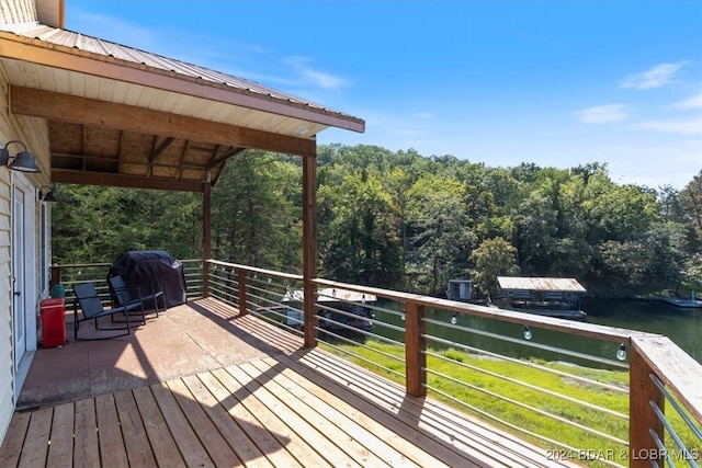 deck with grilling area, a lawn, and a water view