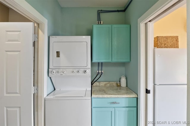 laundry area featuring cabinets and stacked washer / drying machine