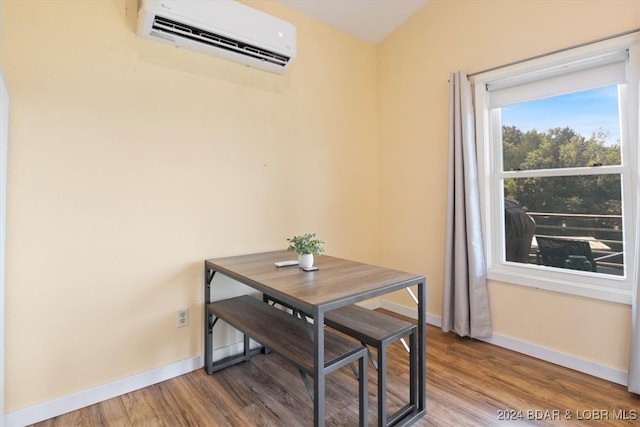 dining room with baseboards, an AC wall unit, and wood finished floors