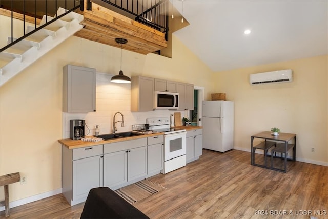 kitchen featuring high vaulted ceiling, white appliances, a wall unit AC, wood counters, and sink