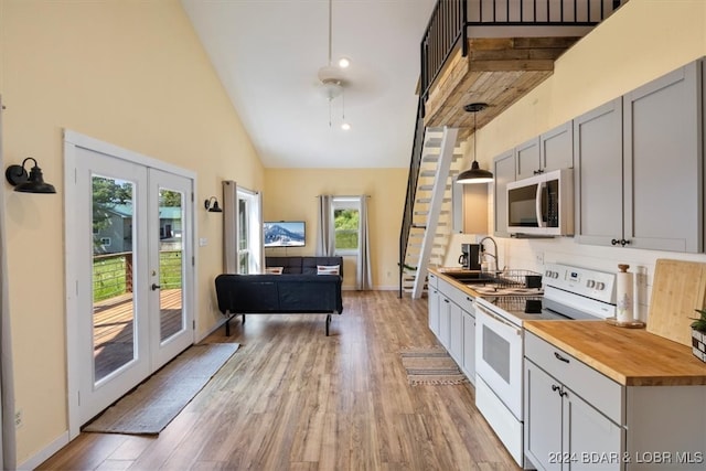 kitchen featuring light hardwood / wood-style floors, hanging light fixtures, high vaulted ceiling, gray cabinetry, and white electric stove