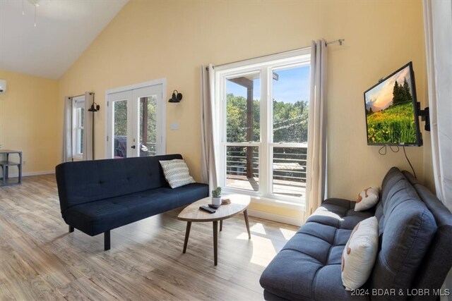 living room featuring high vaulted ceiling, light wood-type flooring, french doors, and plenty of natural light