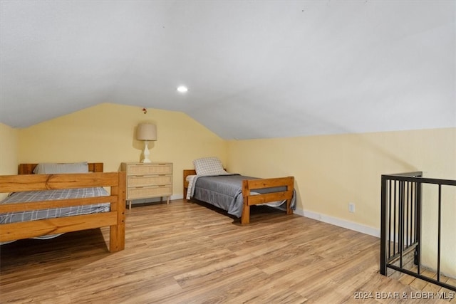 bedroom with light wood-style floors, vaulted ceiling, and baseboards