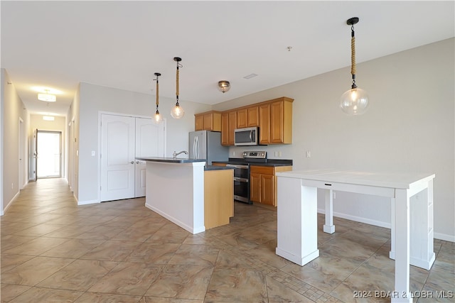 kitchen with decorative light fixtures, stainless steel appliances, an island with sink, and sink