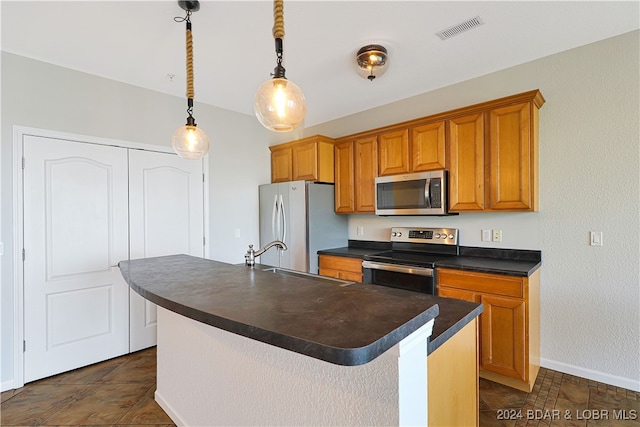 kitchen with pendant lighting, sink, appliances with stainless steel finishes, and a kitchen island with sink