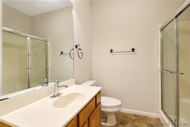 bathroom with vanity, toilet, tile patterned flooring, and a shower with door