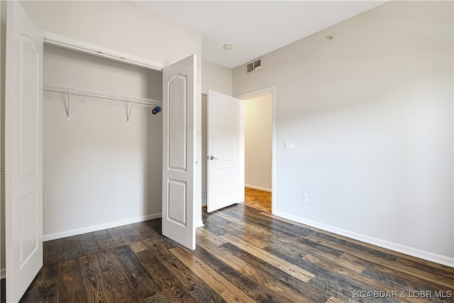 unfurnished bedroom with dark hardwood / wood-style floors and a closet