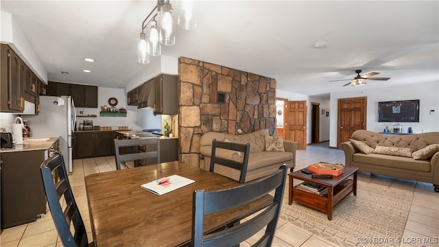 dining space with ceiling fan with notable chandelier and light tile patterned floors