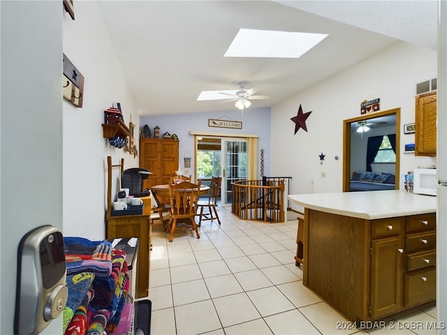 kitchen featuring ceiling fan, french doors, kitchen peninsula, lofted ceiling with skylight, and light tile patterned floors