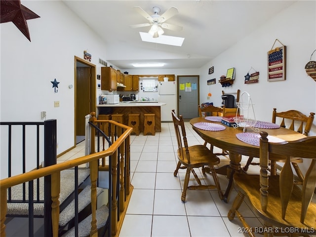 tiled dining space featuring ceiling fan and lofted ceiling with skylight