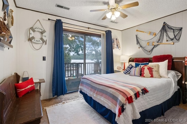 bedroom with wood walls, carpet flooring, a textured ceiling, access to exterior, and ceiling fan