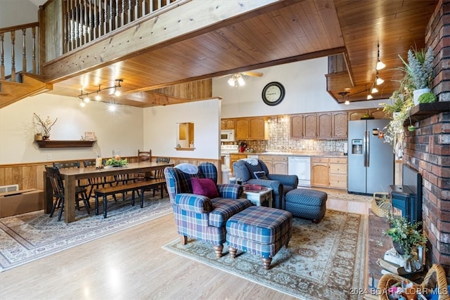 living room featuring light hardwood / wood-style floors, wood ceiling, wood walls, and a wood stove