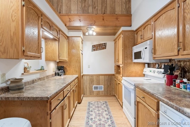 kitchen featuring wooden walls, light wood-type flooring, and white appliances