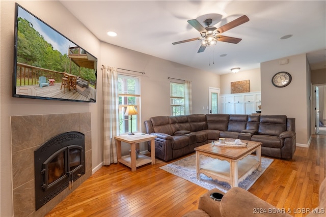 living room featuring light hardwood / wood-style floors, ceiling fan, and a fireplace