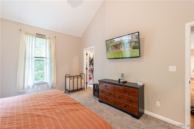 bedroom with light colored carpet, a spacious closet, and high vaulted ceiling