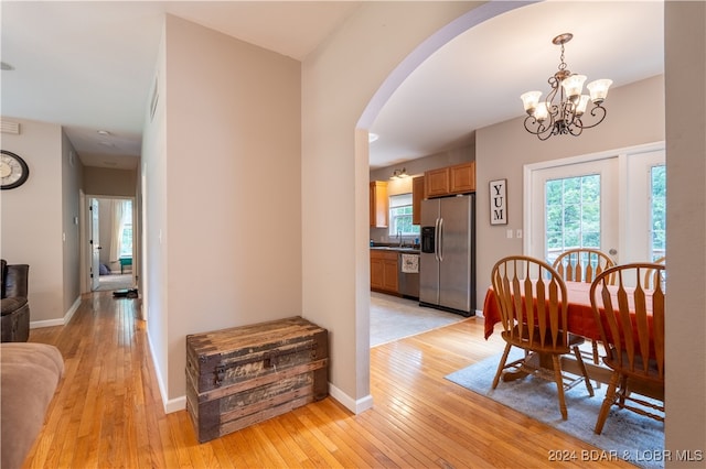 dining space with light wood-type flooring, sink, and a chandelier