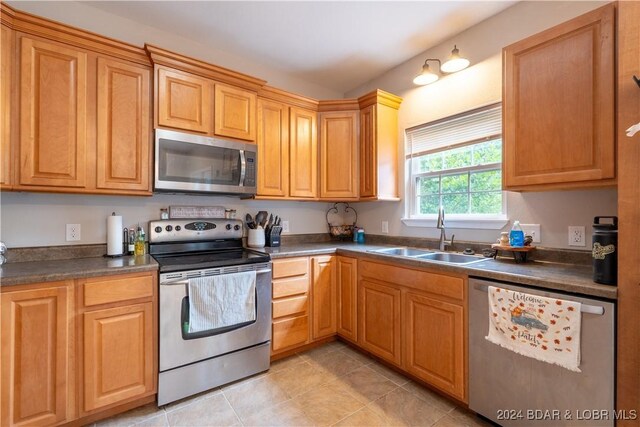 kitchen featuring appliances with stainless steel finishes, light tile patterned floors, and sink