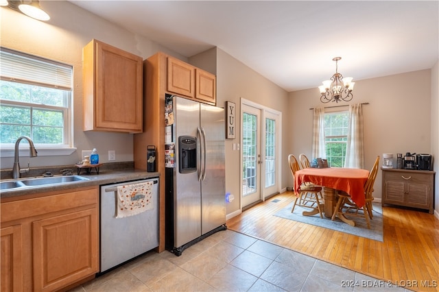 kitchen with hanging light fixtures, sink, light hardwood / wood-style flooring, stainless steel appliances, and an inviting chandelier