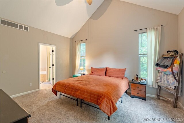 carpeted bedroom with ceiling fan, ensuite bathroom, and high vaulted ceiling