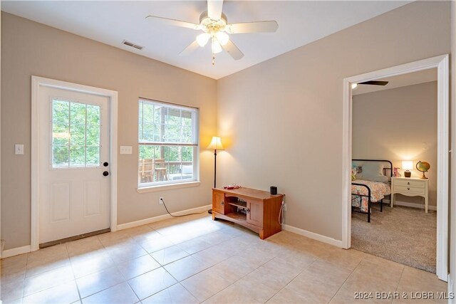 doorway to outside featuring ceiling fan and light tile patterned flooring