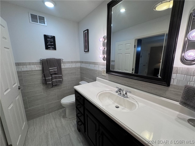 bathroom with vanity, tile walls, and toilet