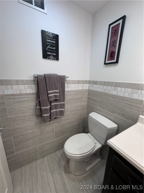 bathroom with vanity, tile walls, and toilet