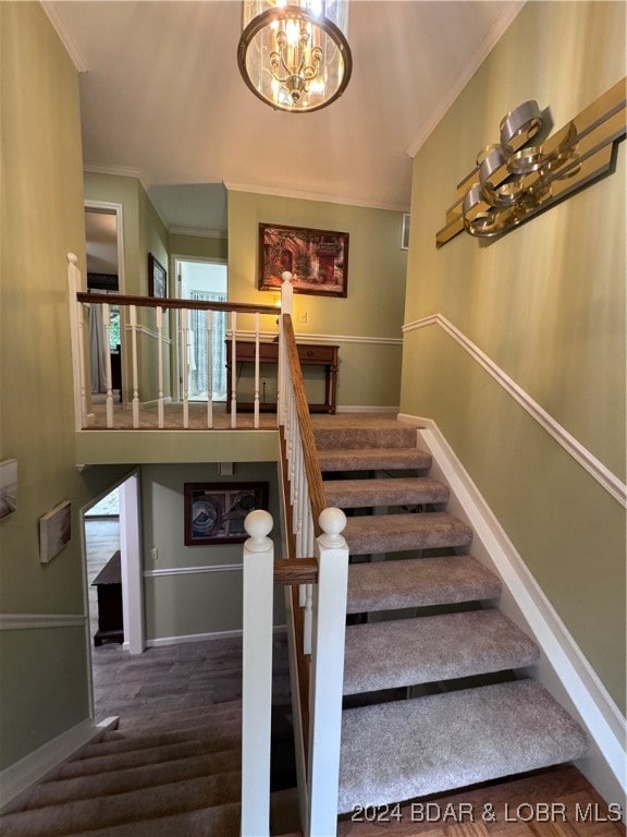 staircase with ornamental molding, a healthy amount of sunlight, and an inviting chandelier