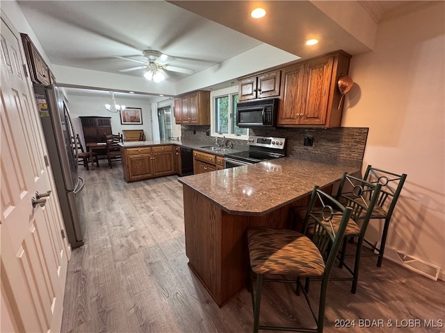 kitchen featuring kitchen peninsula, black appliances, sink, and light hardwood / wood-style flooring