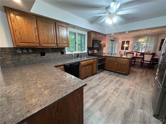 kitchen featuring tasteful backsplash, kitchen peninsula, black appliances, and light wood-type flooring