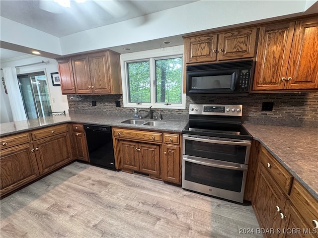 kitchen featuring light wood-type flooring, sink, tasteful backsplash, and black appliances