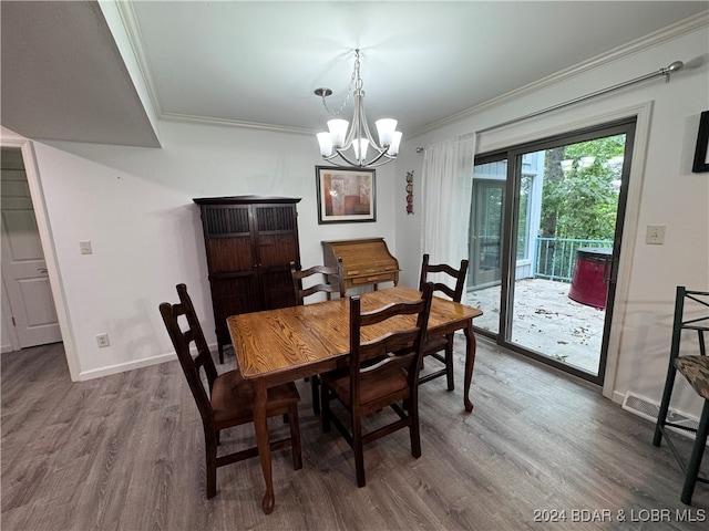 dining space featuring ornamental molding, hardwood / wood-style floors, and an inviting chandelier