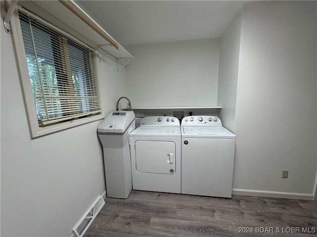 clothes washing area featuring hardwood / wood-style floors and washing machine and clothes dryer