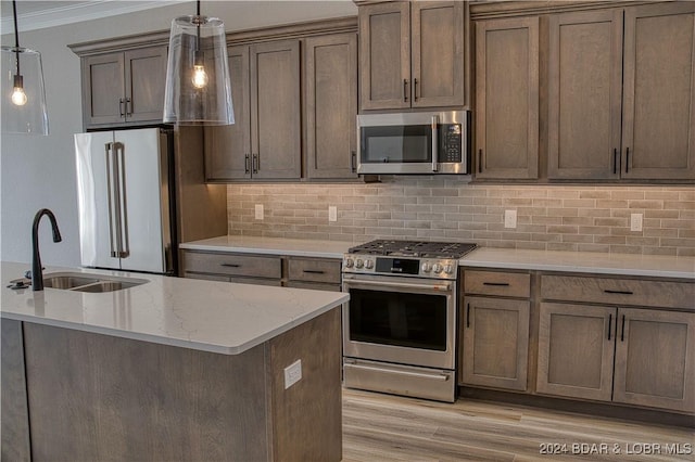 kitchen with appliances with stainless steel finishes, pendant lighting, sink, backsplash, and light stone countertops